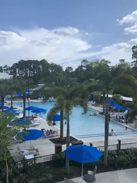 a pool with blue umbrellas and palm trees