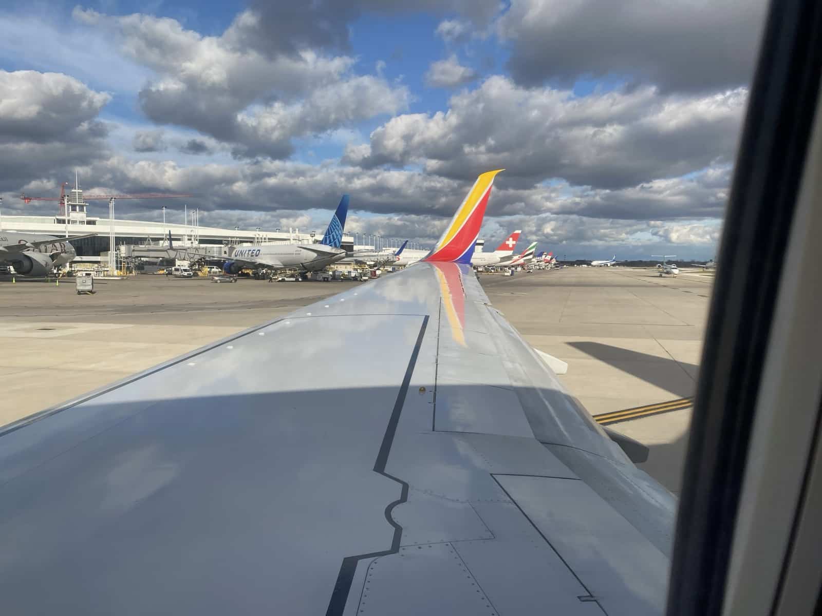 a plane wing with colorful tail fin and tail fin on a runway