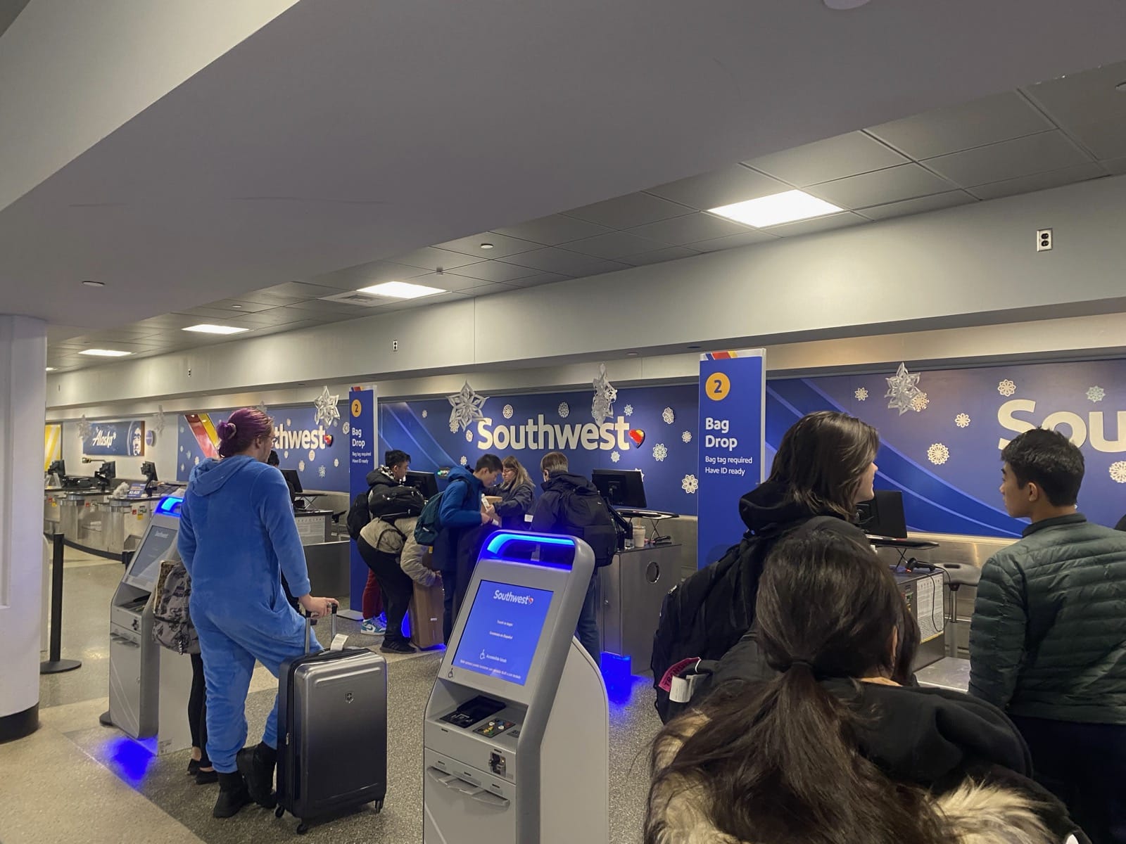 people standing in a line at an airport check-in counter